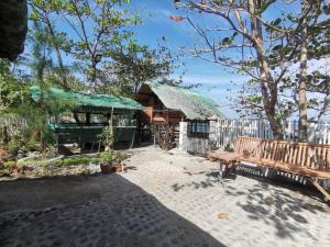 ein Holzgebäude mit einem grünen Dach und einer Bank in der Unterkunft Zeah's Beach Place in Bulusan