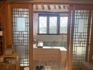 a bathroom with a tub in a room with windows at Hanok Stay - JukRokJungSa in Gurye