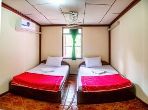 two beds in a small room with a window at Xaymountry Don Khon City Center Residence and Guesthouse in Ban Donsôm