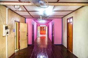 Xaymountry Don Khon City Center Residence and Guesthouse في Ban Donsôm: مدخل مع جدران وردية وأرجوانية وأرضيات خشبية