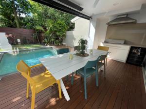 a dining table and chairs on a deck with a swimming pool at Sunshine Beach Gem in Sunshine Beach
