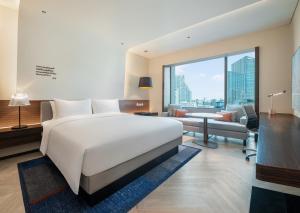 a bedroom with a large white bed and a living room at Le Meridien Bangkok in Bangkok