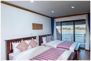 two beds in a room with a balcony at Riverside Chiangkhan in Ban Mai Ta Saeng