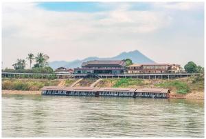 Ein Boot auf einem Fluss, im Hintergrund Gebäude. in der Unterkunft Riverside Chiangkhan in Ban Mai Ta Saeng
