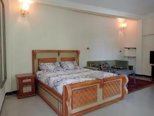ein Schlafzimmer mit einem Bett mit einem Holzrahmen in der Unterkunft Avi Guest House in Addis Abeba