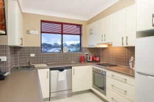 a kitchen with white cabinets and a window at Apollo Unit 7 1st Floor in Narooma