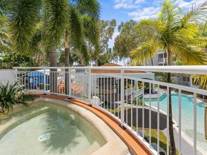 een balkon met een zwembad en palmbomen bij Alassio Beachfront Apartments Palm Cove in Palm Cove