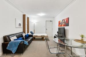 a living room with a black leather couch and a glass table at Perth City Retreat - free parking in Perth