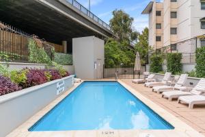 a swimming pool with chaise lounge chairs next to a building at Perth City Retreat - free parking in Perth