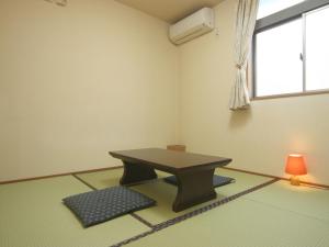 Zimmer mit einem Tisch und einer Lampe auf dem Boden in der Unterkunft プチバスケット in Chiba