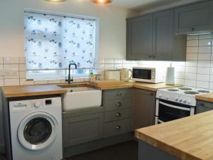 a kitchen with a sink and a washing machine at Nant Y Felin in Llanfairfechan