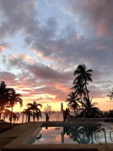 uma piscina com palmeiras e um pôr-do-sol em Hideaway Resort em Maraat