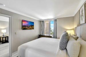 a white bedroom with a large bed and a window at Lavish beachfront condo with rooftop pool/spa/gym in Marco Island +19 photos