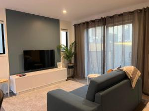 uma sala de estar com um sofá e uma televisão de ecrã plano em Luxurious inner city 2 bed pad em Christchurch