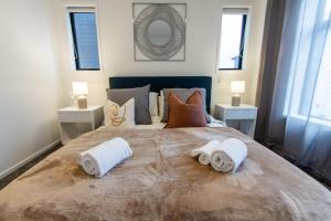 um quarto com uma cama grande e toalhas em Luxurious inner city 2 bed pad em Christchurch