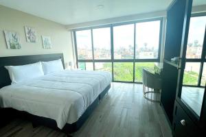 een slaapkamer met een groot bed en grote ramen bij Luxury 2BR Condo Rosarito (G) in Rosarito