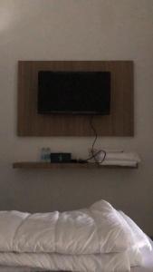 a television on a wall above a bed at Damai Guest House Cirebon in Cirebon