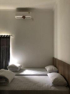 a bedroom with two beds and a window at Damai Guest House Cirebon in Cirebon
