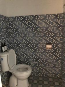 a bathroom with a toilet and a tiled wall at Damai Guest House Cirebon in Cirebon