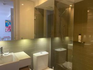 ein Badezimmer mit einem WC, einem Waschbecken und einem Spiegel in der Unterkunft Bayside Melbourne Apartment in Melbourne
