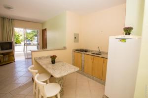 une cuisine avec un comptoir, une table et des chaises dans l'établissement Apartamentos Praia Campeche 50m do mar, à Florianópolis