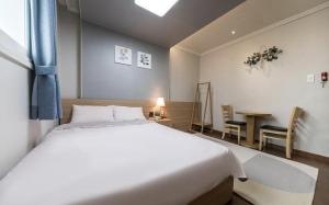 a bedroom with a large white bed and a table at Ellui Hotel Jeju in Jeju