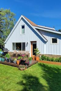 a white barn with chairs and flowers in a yard at Luxury DT Cottage - Free Parking - Self Check-In in Anchorage