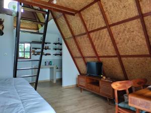 a bedroom with a bed and a desk with a tv at Magical Breeze Cabin in Angsri