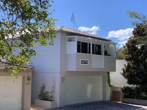 a white house with a white garage at HighTide- luxury apartment, almost on the beach. in Corlette