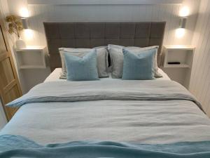 Una gran cama blanca con almohadas azules. en HighTide- luxury apartment, almost on the beach., en Corlette