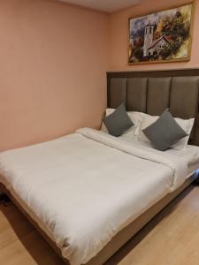 un letto con lenzuola e cuscini bianchi in una stanza di Heritage View a Ooty