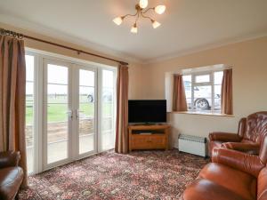 a living room with a couch and a television and windows at Cliff Farm No 2 Cottage in Burton Bradstock