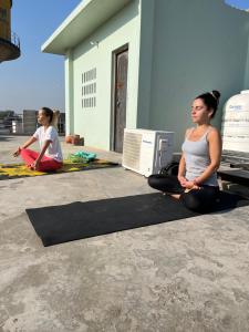 two women sitting on a yoga mat in front of a building at Prabhu Sadan home stay in Govardhan