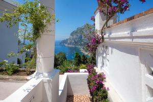 a view of the ocean from a white building with flowers at Villa Mariuccia Capri in Capri