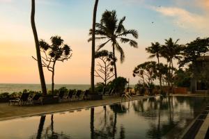 a swimming pool with palm trees and the ocean at Earl's Regent Negombo in Negombo