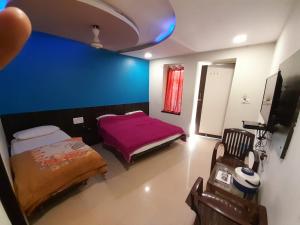 a room with two beds and a blue wall at Mooljis Palace in Mount Ābu