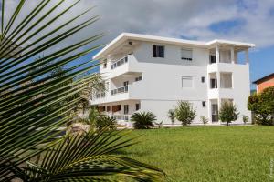 um edifício branco com uma palmeira em frente em Apartamentos Praia Campeche 50m do mar em Florianópolis