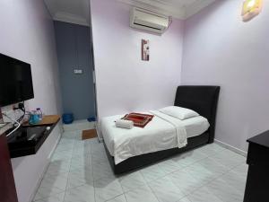 ein Schlafzimmer mit einem Bett und einem TV in der Unterkunft HOTEL RAUDHAH Kerteh in Kertih