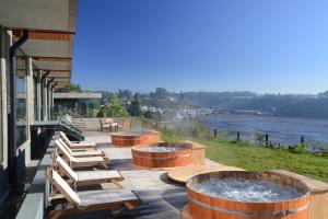 a patio with three large wooden tubs with chairs and a fountain at Enjoy Chiloé in Castro