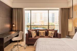 a bedroom with a bed and a couch and a window at Le Royal Meridien Beach Resort & Spa Dubai in Dubai