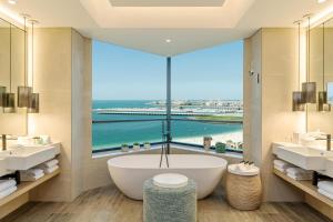 a bathroom with a tub and a large window at Le Royal Meridien Beach Resort & Spa Dubai in Dubai