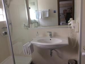 a white bathroom with a sink and a shower at Hotel Die Post in Offenbach