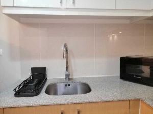 a kitchen counter with a sink and a microwave at Uptown Parksuites Apartments Tower 1 BGC by PH Staycation in Manila