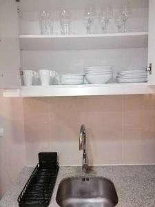 a kitchen counter with a sink and dishes on a shelf at Uptown Parksuites Apartments Tower 1 BGC by PH Staycation in Manila
