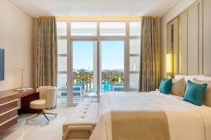 Al Messila, A Luxury Collection Resort & Spa, Doha في الدوحة: غرفة نوم بسرير كبير ومكتب ونافذة