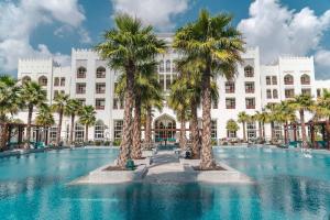 a hotel with palm trees in front of it at Al Messila, A Luxury Collection Resort & Spa, Doha in Doha