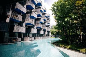 a building with a swimming pool in front of it at The Deck Condo Studios Patong w/ pool fitness in Patong Beach