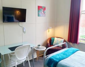 a room with a bed and a table and a tv at Extended Stay City Hostel in Dunedin