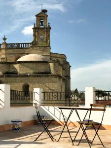 a building with a clock tower and a table at Apartamentos Makao Puerta del Olivillo in Jerez de la Frontera