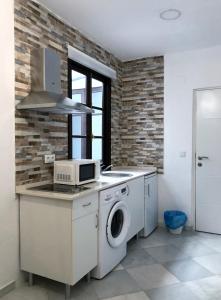 a kitchen with a washing machine and a microwave at Apartamentos Makao Puerta del Olivillo in Jerez de la Frontera